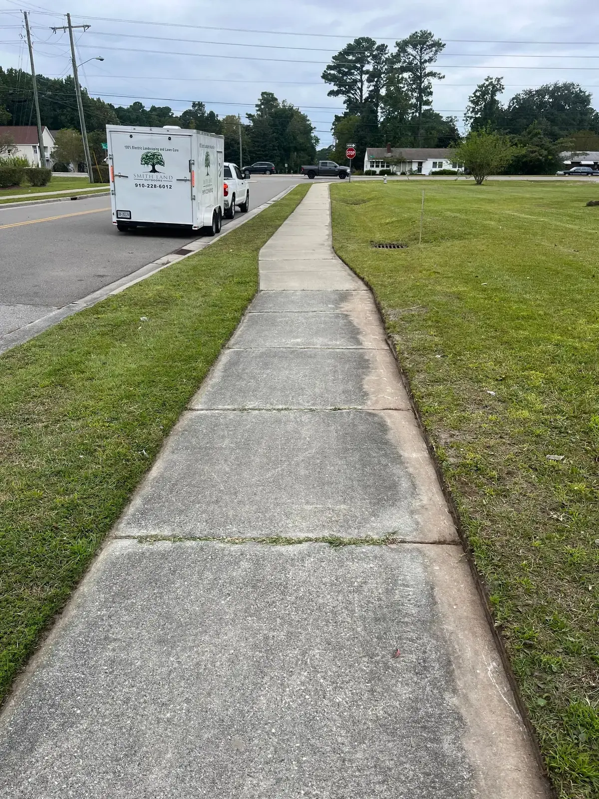 Crisp walkway edge between a mown lawn and concrete path