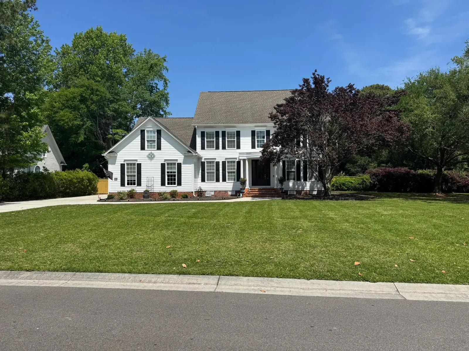 Clean lawn and drive at a white colonial home
