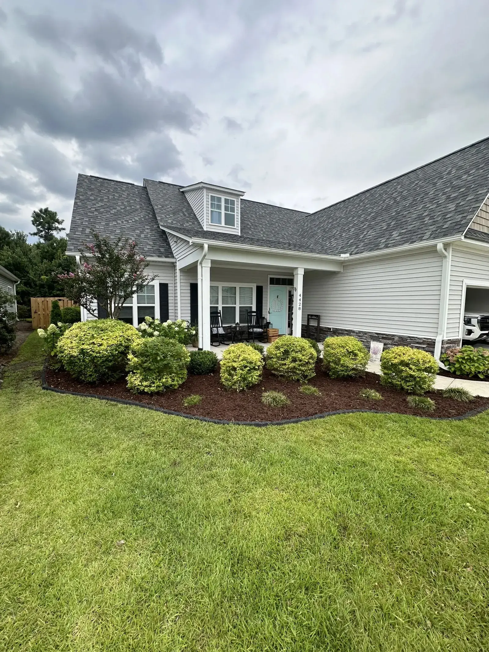 Rounded foundation shrubs and mulch beds at a craftsman home