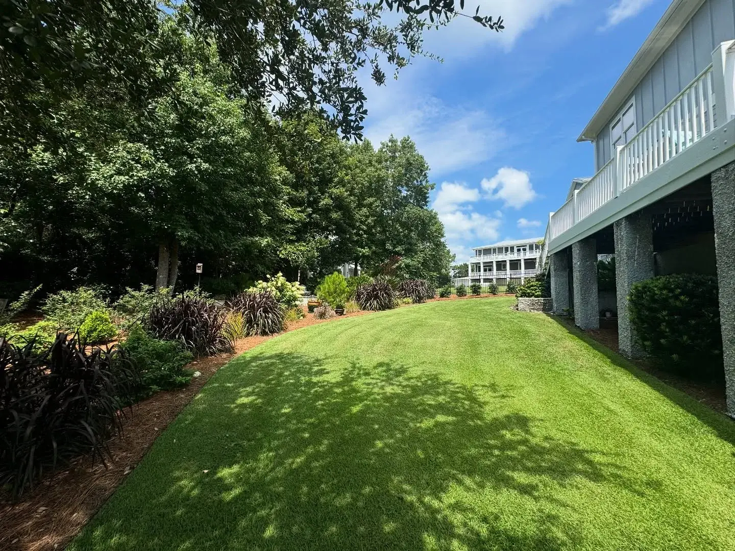 Maintained lawn and beds running alongside a waterfront house