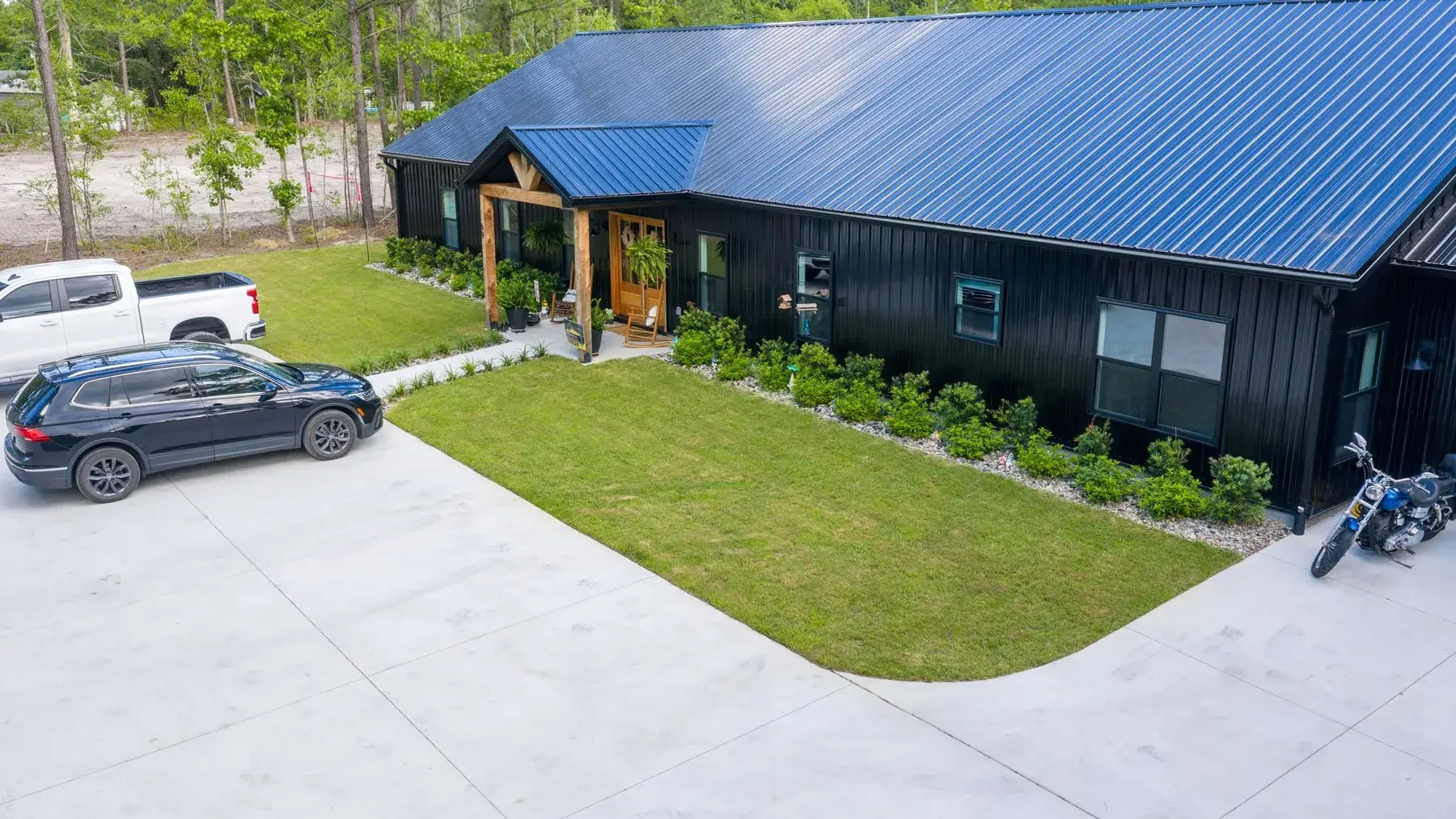 New plantings and river rock border along a black metal-roofed home